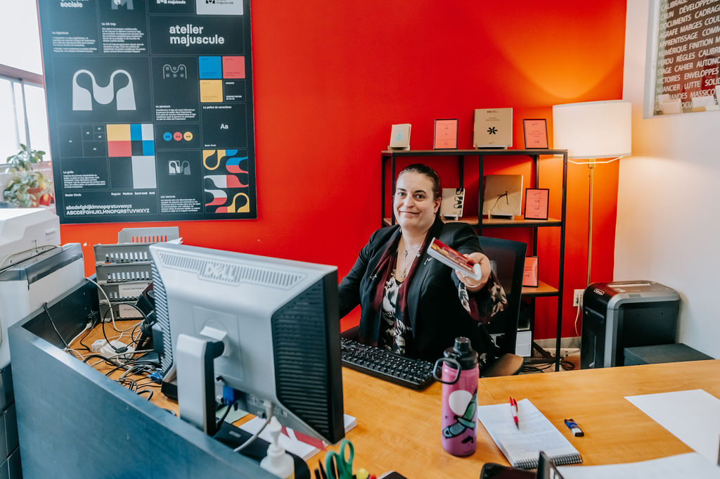 Personne administration de l'Atelier majuscule qui tend un livre